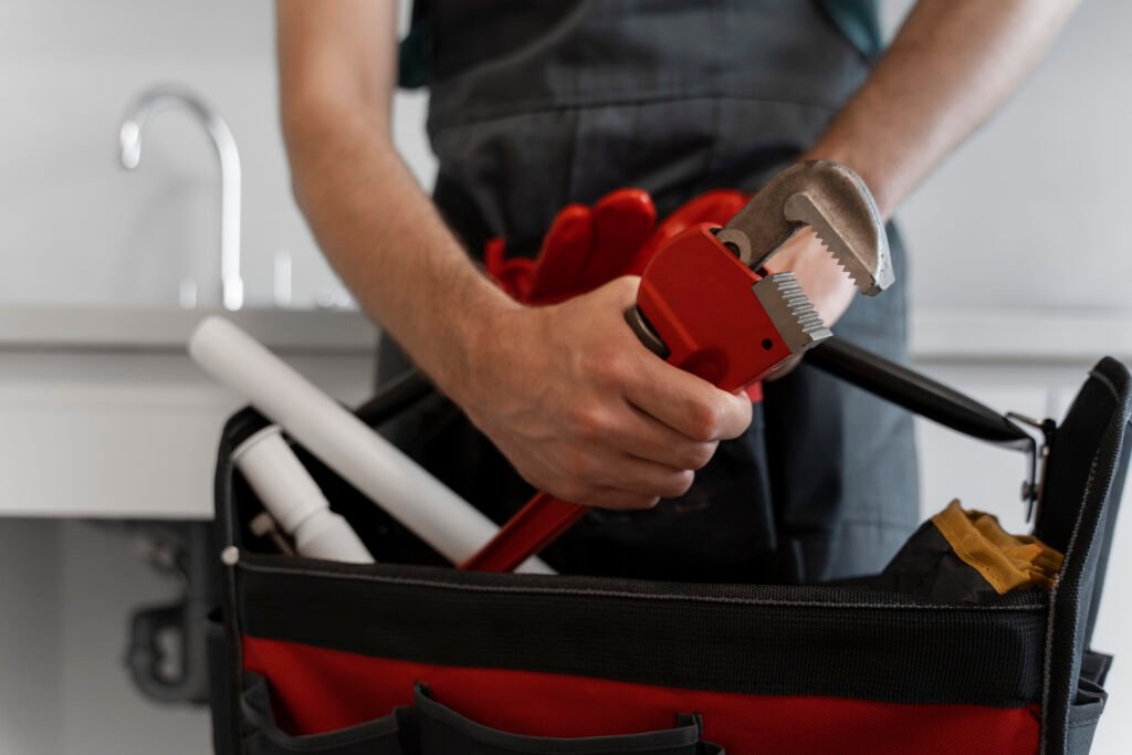 Plombier avec sa pince et sa caisse à outils