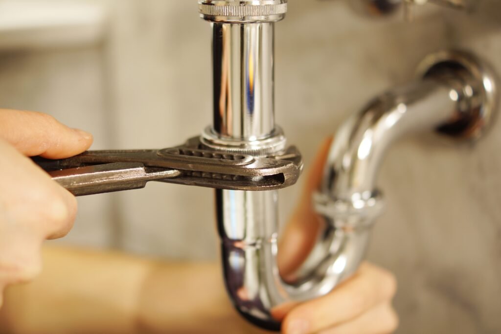 Plombier resserrant un siphon chromé sous un lavabo