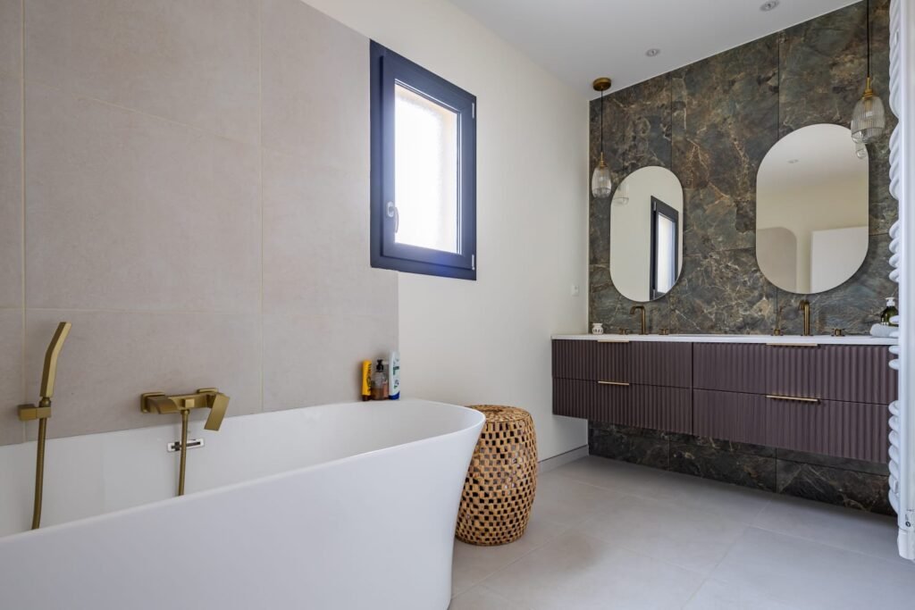 Salle de bain rénovée avec baignoire îlot et robinetterie dorée